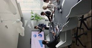 Diverse businesspeople discuss financial report in charts, diagrams, graphs seen on TV screen in boardroom, develop sales growth strategy, reviewing statistic at group presentation led by CEO or coach