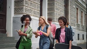 Group of happy teenagers together in front of school, back to school concept.