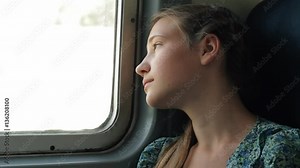 Teenage girl looking through window riding on train