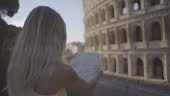 Young woman in Rome at the Colosseum looking at tourist map for...