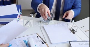 Man and woman sorting documents with hole punch and stapler and putting them in folder 4k movie. Paper work concept