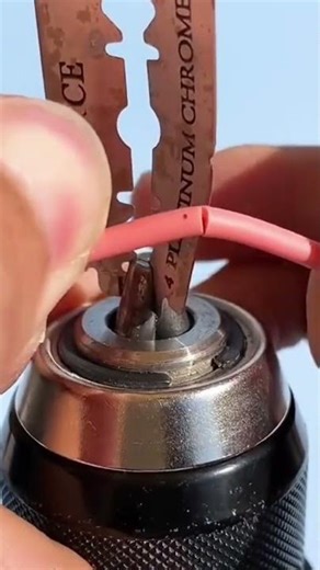 the process of stripping the layers of electrical cable wire using a razor blade attached to a drill