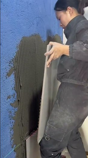 Worker using specialized tool to install large wall tile