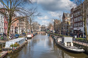 View on Amsterdam from street with row of shops; tram, tourists and...