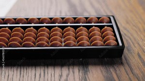 Sliding in front of Japanese abacus soroban placed on practice sheets for teaching kids mental arithmetics.