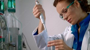 Chemist woman working with chemical liquid in lab closeup. Female chemist doing chemistry research. Scientist working on chemical research. Chemist using pipette with liquid in chemistry laboratory