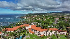 Aerial Kauai Hawaii beach condominium homes shoreline. Expensive luxury homes, resort, condominium and golf club near coast. Recreation and tourism. Economy tourism based. Tourist enjoy warmth.