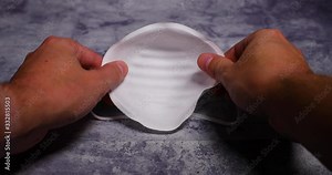 Men's hands first person view taking and putting protective face mask on camera white mask from threat like corona Covid-19 virus protects mouth and nose from dark black board capture in 4k 60fps