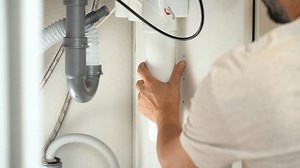 Close up of plumbers hands install water filter. Replacement water purifier. Repairman changes water filter cartridges in kitchen under kitchen sink. Osmosis