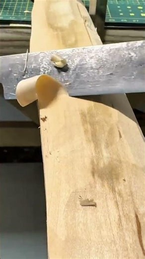 carving and shaping a piece of light wood into a beautiful bow shape using a very sharp black knife