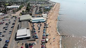 Aerial footage of the British seaside town of Hunstanton Norfolk, showing holiday makers relaxing and having fun on the sunny beach in the summer time. Stock Video