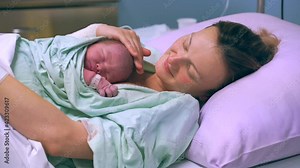 Mother and newborn. Child birth in maternity hospital. Young mom hugging her newborn baby after delivery. Woman giving birth. First moments of baby life after labor.