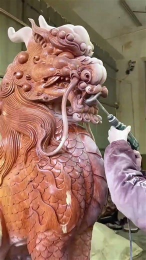 Polishing a carved wooden dragon statue to smooth the surface and enhance its detailed appearance