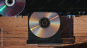 The compact disc is inserted into the DVD player. Male hand loads CD into a CD player tray close-up. Music, movies, or data recorded on a laser optical information storage medium. Loading Compact Disc