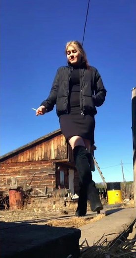 Cute Girl in high heels suede boots smoking and spitting outside