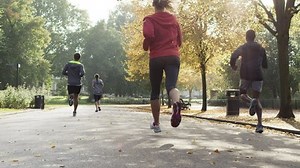 Group of runners running in park wearing wearable technology connected devices