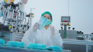 Workers producing surgical mask in modern factory, Covid-19 protection and medical concept.