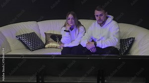 Couple Watching TV Together at Home, The man comes before the woman and watches the TV at the same time