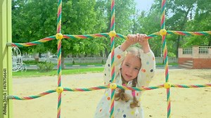 Little girl on the playground, climbing rope net.