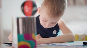 Drawing. Little boy with pencil coloring at home. Child draws at the table. Psychology of the child's personality. Help gaining confidence. Creativity and education concept.
