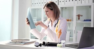 Traumatologist examines x-ray and legs and model of knee joint