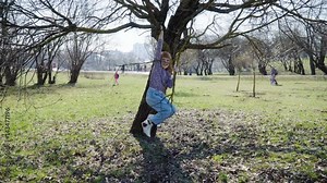 Redhead girl is playing on a tree, hanging and climbing, steadicam shot