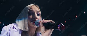 Fans Experiencing a Musical Performance by a Talented Young Singer. Beautiful Pop Band Lead Singer Performs on Stage With a Blend of Emotion and Energy, Singing Songs to Audience. Anamorphic Shot