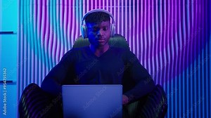Hacker programmer computer worker gamer African American man in headphones male guy typing laptop online data internet security gaming play video game innovation futurism sitting at chair cyber crime