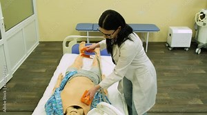 A female doctor at a medical school shows the operation of a defibrillator on a model mannequin. Dummy model for teaching medical practice. Close-up