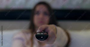 Woman holding remote control in her hand switches channels on the TV