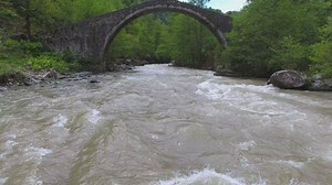 River flowing under an old stone bridge with a woman - Free Stock Video