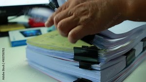 Businessman hands working in Stacks of paper files for searching information on work desk office, business report papers,piles of unfinished documents achieves with clips indoor,Business concept