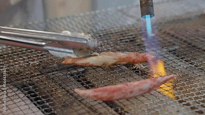 This close up video shows a torch cooking crab meat on a grill.