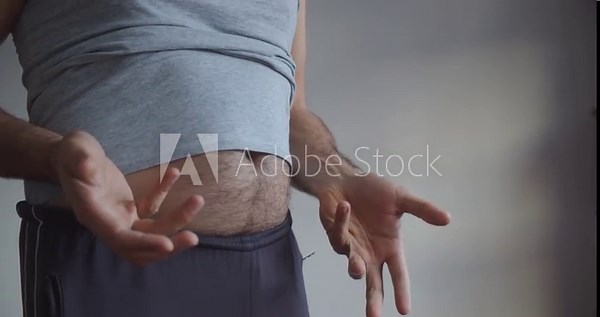 An adult man with a bare hairy beer belly actively gesticulates. Close-up on the stomach and arms