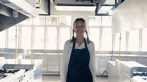 4K Slow, Close-up asian girl wearing chef clothes apron braid hair tight on both sides keep it clean when coming cooking classes, Walked up camera was recording video smiling while looking at camera.