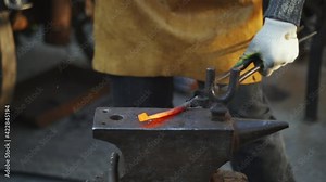 Forge workshop. Smithy manual production. Hands of smith with hammer hit on glowing hot metal, on the anvil, the forging process in slow-mo. Blacksmith makes iron products for manufacture of fireplace
