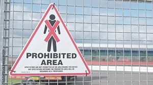 Unsafe or restricted area signs. Pedestrian traffic is prohibited. Pedestrians prohibition. Handheld shot of rectriction sign with cars driving fast in the background behind the fence.