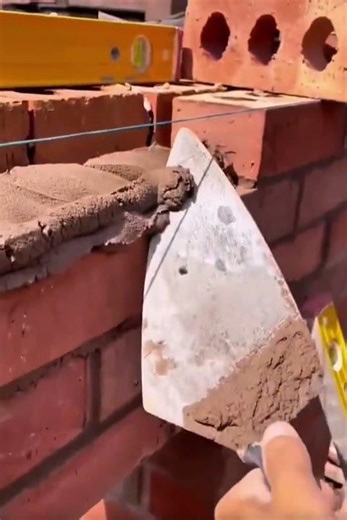 Spread the cement mixture with a trowel on the wall surface to install a brick #construction #shorts