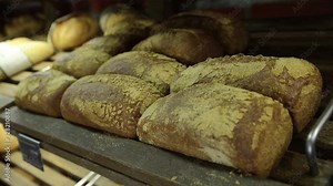 Different kinds of bread loaves on display in market. Fresh bread stacked on a shelves in bakery. Fresh baked bread for sale on shelf. Traditional hand made bread at pastry store.