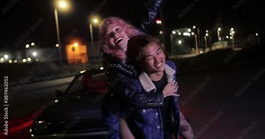 Man giving girlfriend piggyback ride at night on parking lot