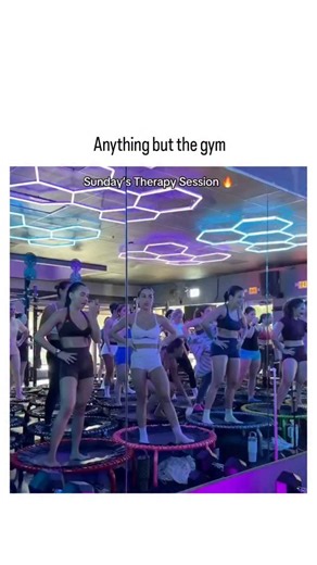 trendpluse_offical on Instagram: "The post shares a 42-second video of a lively group trampoline workout class, where participants in neon outfits bounce rhythmically while lifting light weights to upbeat music, captioned "Anything but the gym" to poke fun at unconventional fitness trends. Replies reveal divided opinions: many praise its fun factor and intensity—requiring core strength, balance, and cardio—while others note it's essentially gym training in disguise, with humorous takes like view