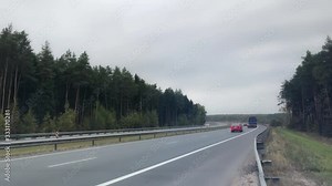 Time Lapse. Large number of cars and trucks travel on the freeway. Road goes beyond the horizon. Pine forest on both sides of the motorway. Clouds float in the sky. Daytime. TimeLapse Ultra HD footage