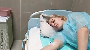 Coronavirus epidemic. covid-19. Weak, emaciated young woman is lying in bed with a catheter in a vein on her arm