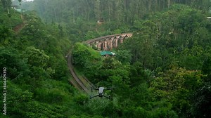 Drone of Nine Arch Bridge in Sri Lanka at sunrise. Historic railroad surrounded by jungle connects hill towns, iconic travelers, photographers. Empty train tracks await adventure amid serene nature.