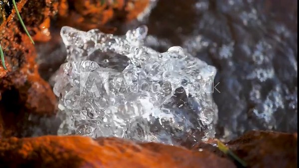 Pure drinking mountain water pulsating and splashing in a natural spring among stones covered with ginger mineral deposits. Slow motion splashing water in a spring. Natural pure water