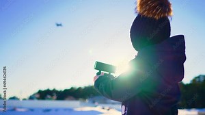 Happy boy plays with a drone in nature. Child controls the drone using a remote control.