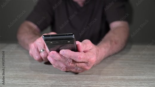senior citizen uses a new smart phone to surf the internet and read the news