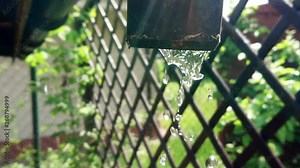 Water dripping from the gutter in slow motion. Drops of crystal clear water falling from the pipe. Ecology, water saving and natural environment concept.