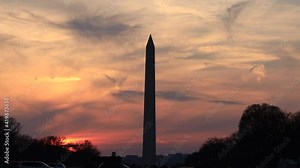 A time-lapse of a crimson red sunset and clouds behind the Washington Monument in Downtown Washington, DC. Airplane traffic and vapor trails are seen in the sky.