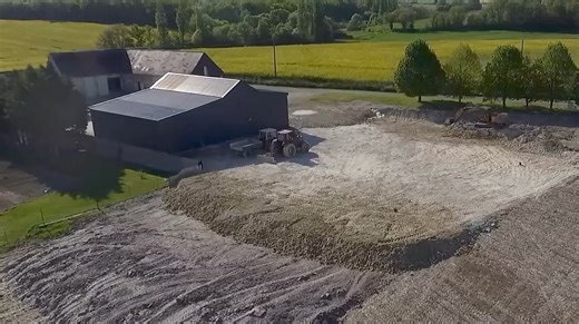 Mise en perspective de l’emplacement du futur hangar métallique Le travail de terrassement réalisé à la lame niveleuse et à la pelleteuse est presque achevé Nous avons décapé et isolé les 20 centimètres de terre végétale pour ne pas la condamner dessous la construction. Le but est qu’un jour, je ne sais encore où, cette terre continue de remplir son rôle nourricier | David Forge, la Chaîne Agricole